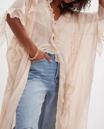 Sheer cream ruffle duster layered over a lace cami and light-wash jeans.