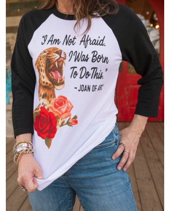 Woman wearing white and black raglan tee with leopard, roses, and Joan of Arc quote: “I Am Not Afraid. I Was Born To Do This.”